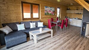 Een gezellig interieur van een vakantiehuisje met een bank, een eettafel, stoelen en een keukenhoek.