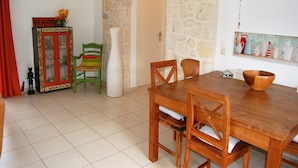 Un comedor con una mesa y sillas de madera, un aparador con puertas de cristal, una pared de piedra y una lámpara colgante.