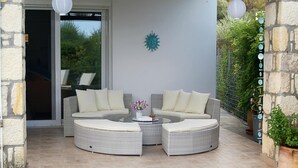 Un espacio de descanso techado al aire libre con mobiliario de mimbre y un elemento decorativo en la pared.