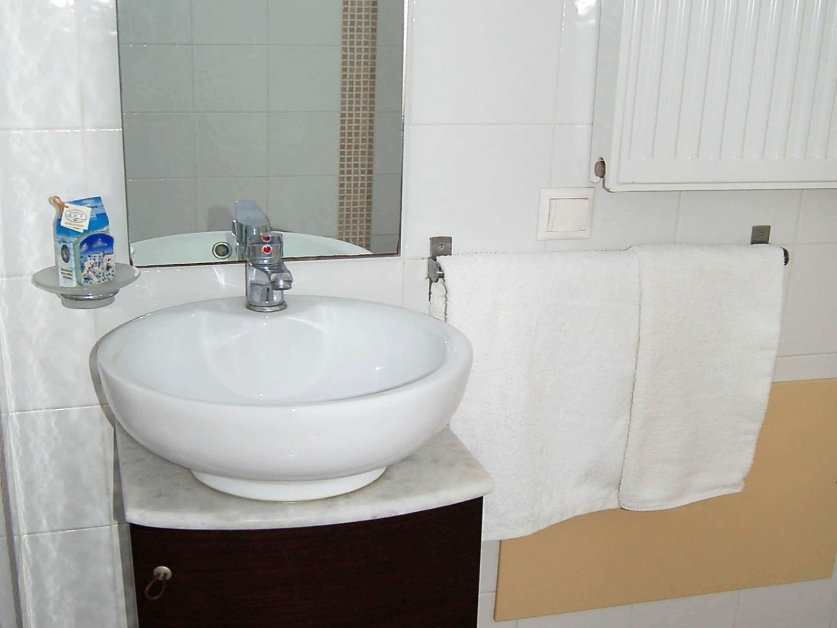 A bathroom with a white sink, a mirror, and a towel rack.