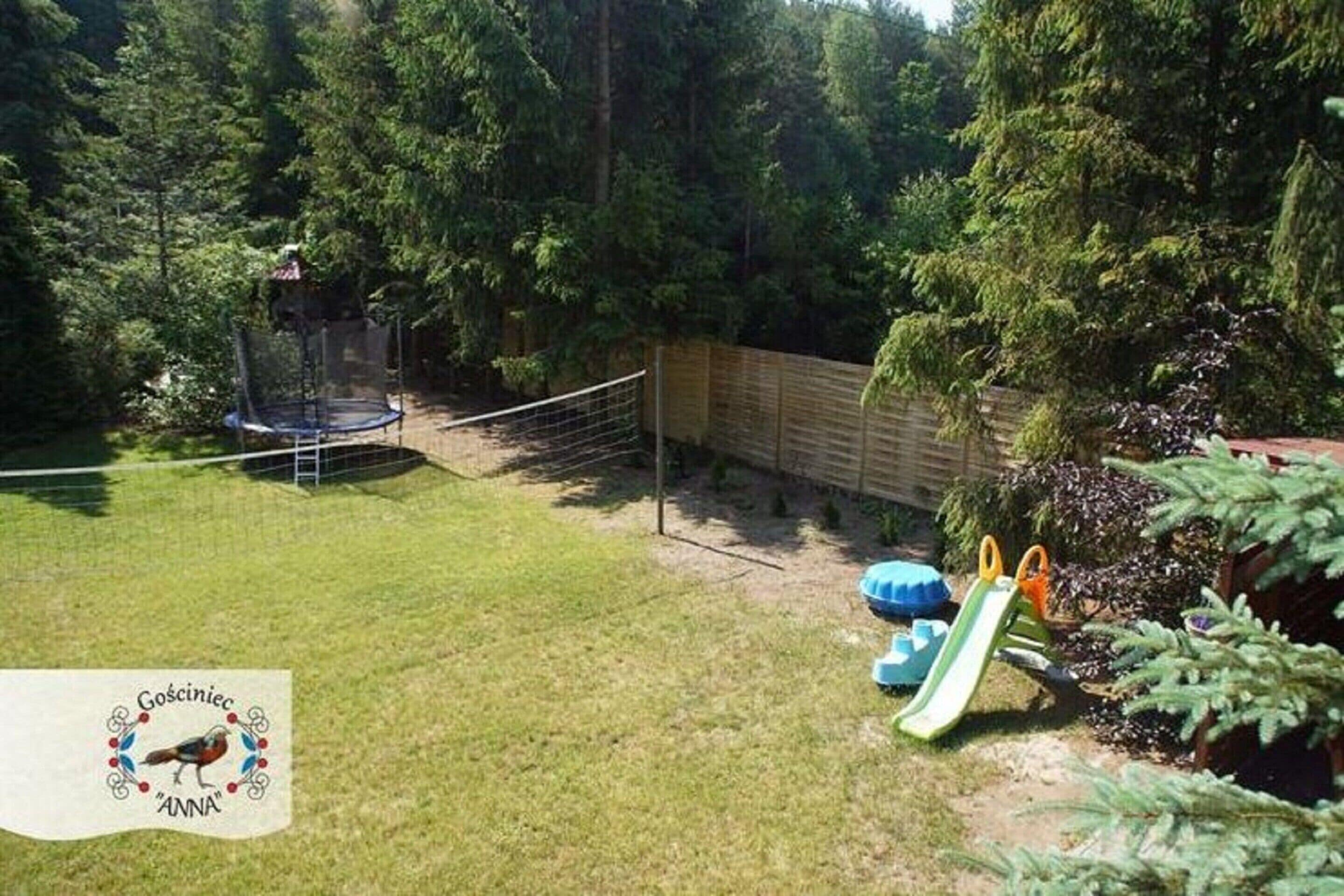 Un patio trasero con un trampolín, un tobogán y una valla de madera.
