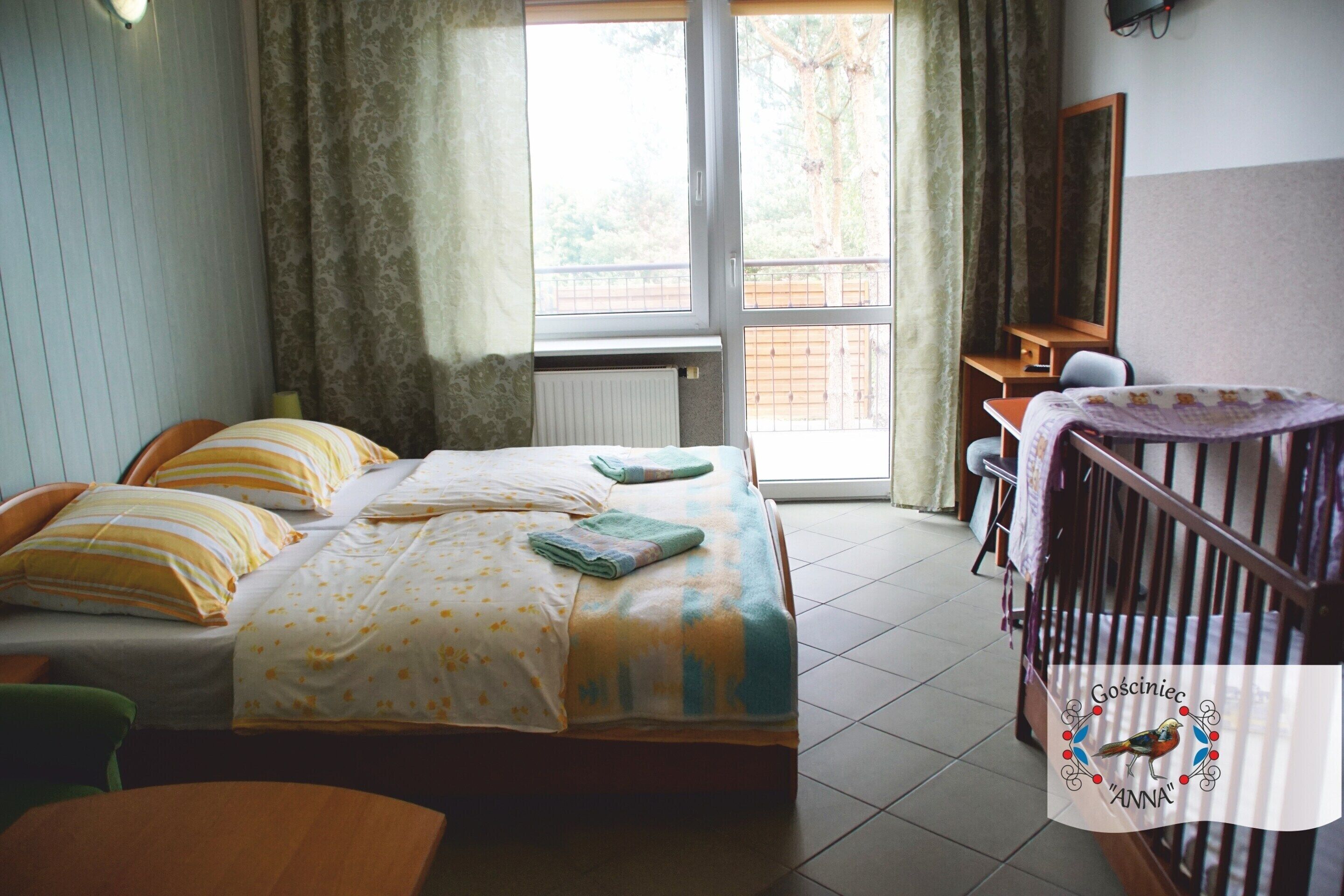 A bedroom with a bed, a desk, a chair, and a crib.