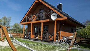 A two-story wooden house with a balcony, a satellite dish, and a hammock. - Lovely House Overlooking the Lake, Near the Sea, Ideal for 9 People (Mielno)