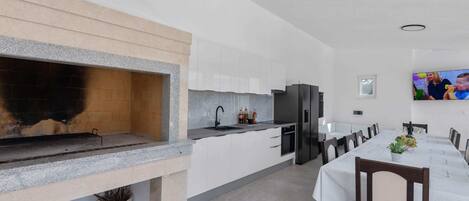 A modern kitchen with a built-in oven, a dining area with a table and chairs, and a TV mounted on the wall.