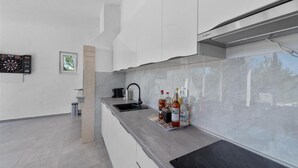 Una cuina moderna amb armaris blancs, taulell negre i campana extractora d'acer inoxidable.