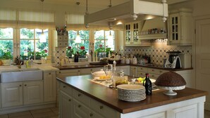 Una cocina espaciosa con una isla grande, mucho espacio en la encimera y vistas a un jardín a través de las ventanas.