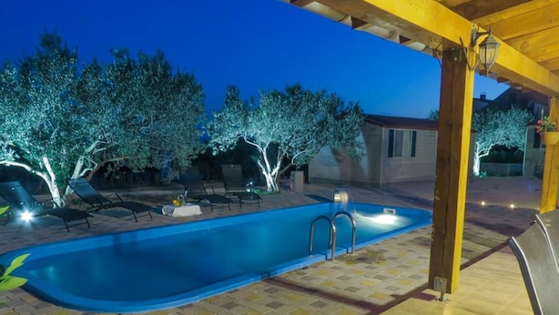 A swimming pool with a tiled deck, lounge chairs, and a pergola structure. - Alluring Holiday Home in Pakoštane With Swimming Pool (Pakostane)