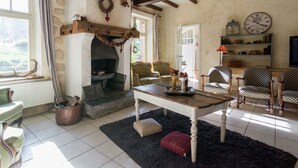 A cozy living room with a fireplace, wooden beams, a chandelier, and a clock on the wall. - Bievre Forest-edge Retreat (Bievre)