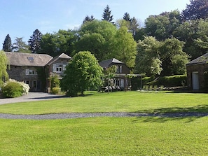 A residential property with a well-maintained lawn, a gazebo, and stone buildings.
