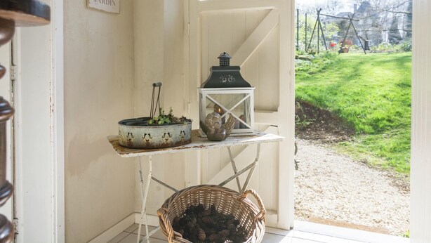 A rustic interior with a sign reading "JARDIN," a rustic lantern, and a wicker basket on a small table. - Bievre Forest-edge Retreat (Bievre)