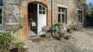 A stone building with a wooden gate, a white door, and a gravel driveway. - Bievre Forest-edge Retreat (Bievre)