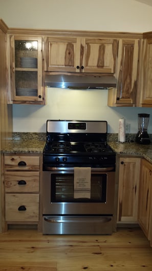 Gas stove with granite counters, dishwasher and refrigerator.