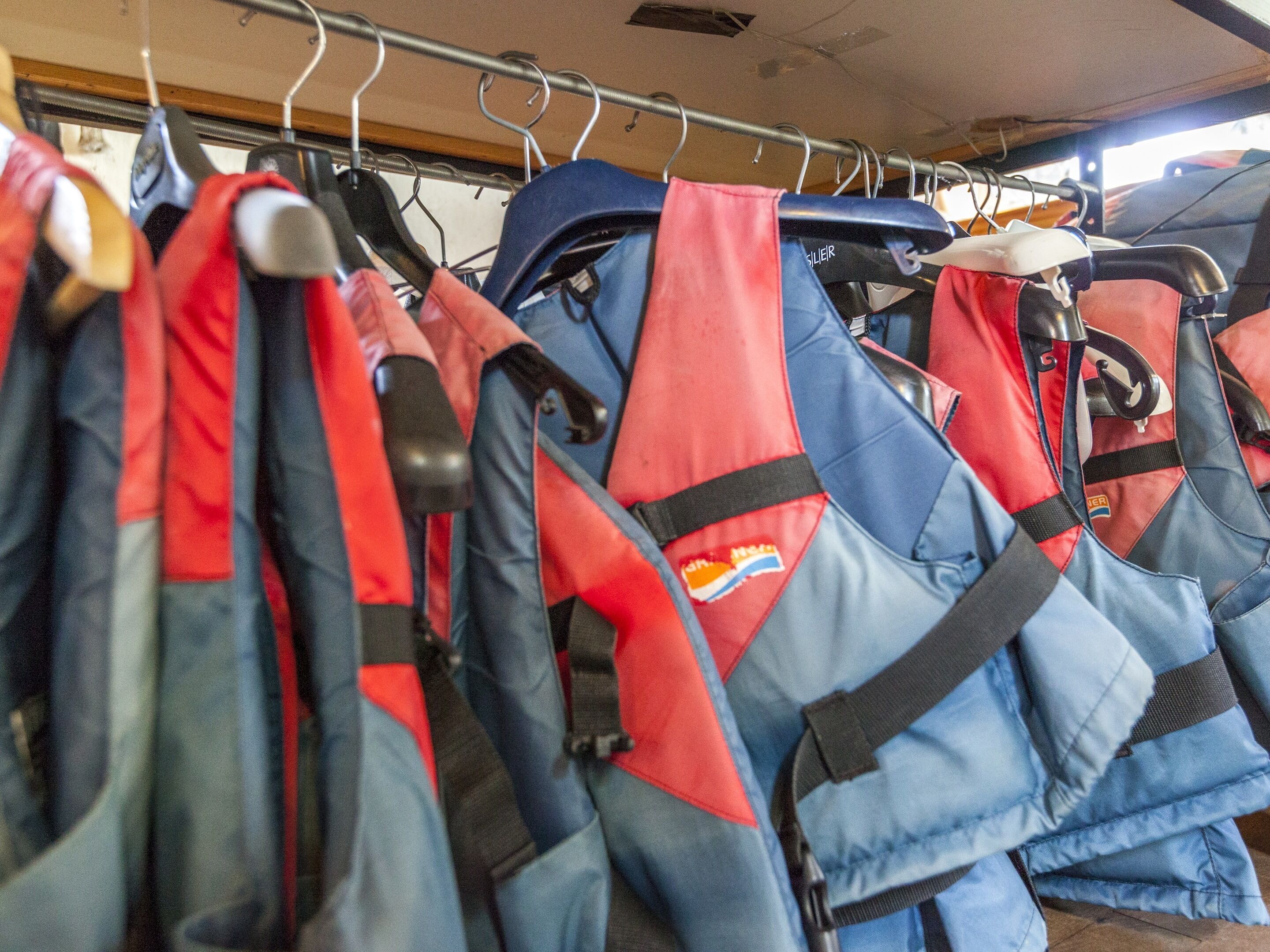 A rack of life jackets in a storage area.