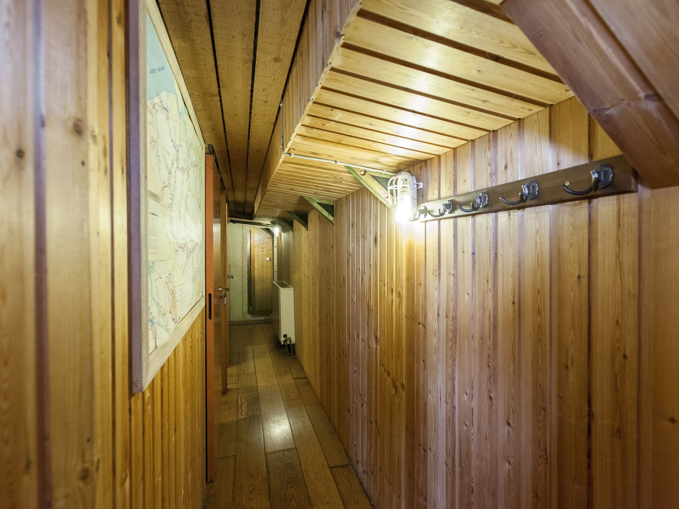 A narrow hallway with wooden walls and a sloped ceiling.