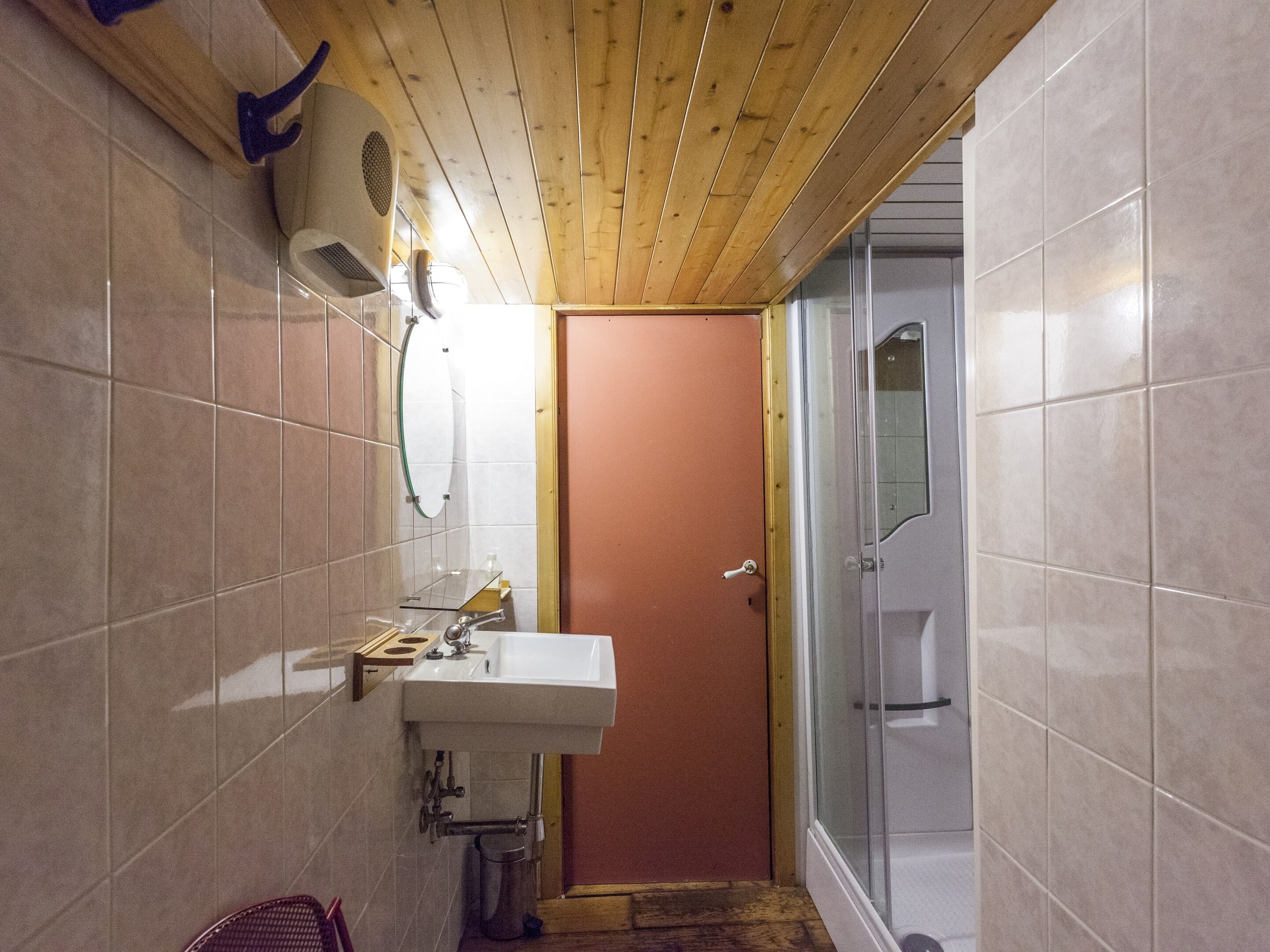 Ein Badezimmer mit Holzboden, einem Waschbecken, einem Spiegel und einer Duschkabine.