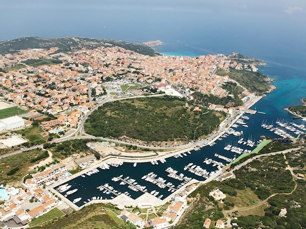 Stunning coastal town with a marina, surrounded by lush greenery and hilly terrain.