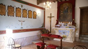 Interno di una chiesa con un altare in legno, panche e dipinti religiosi alle pareti.