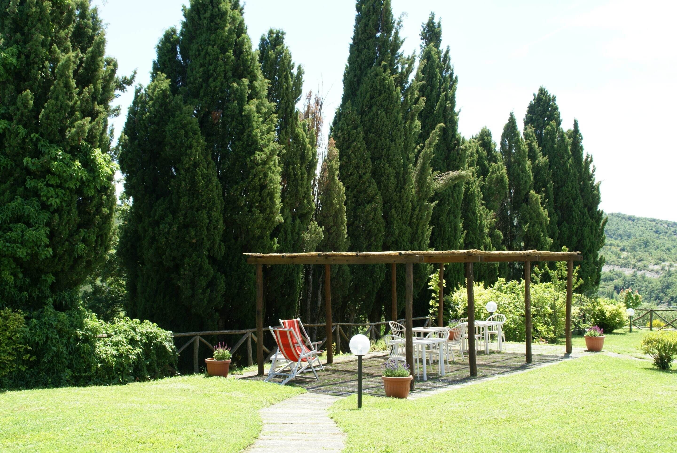 A garden patio with a pergola, outdoor seating, and potted plants.