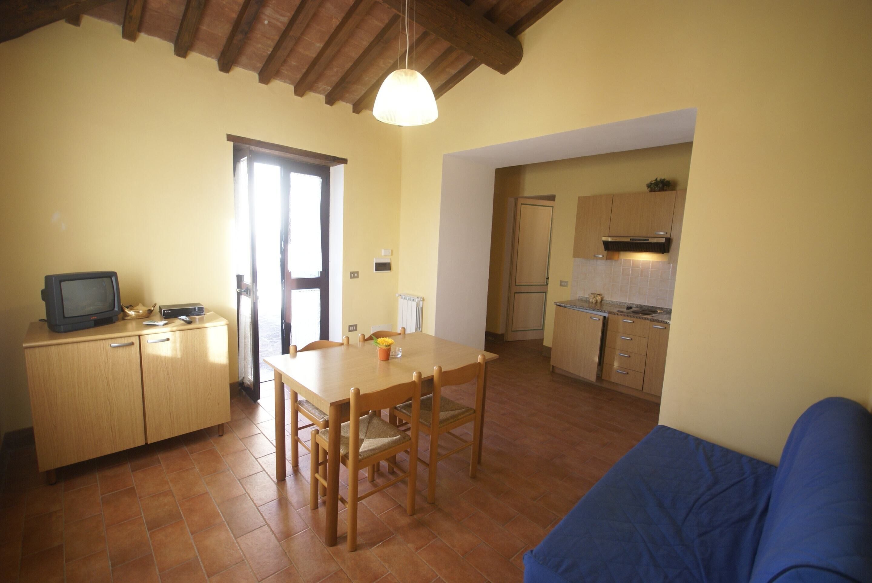 A compact kitchen with a dining area, wooden cabinets, and a blue sofa.