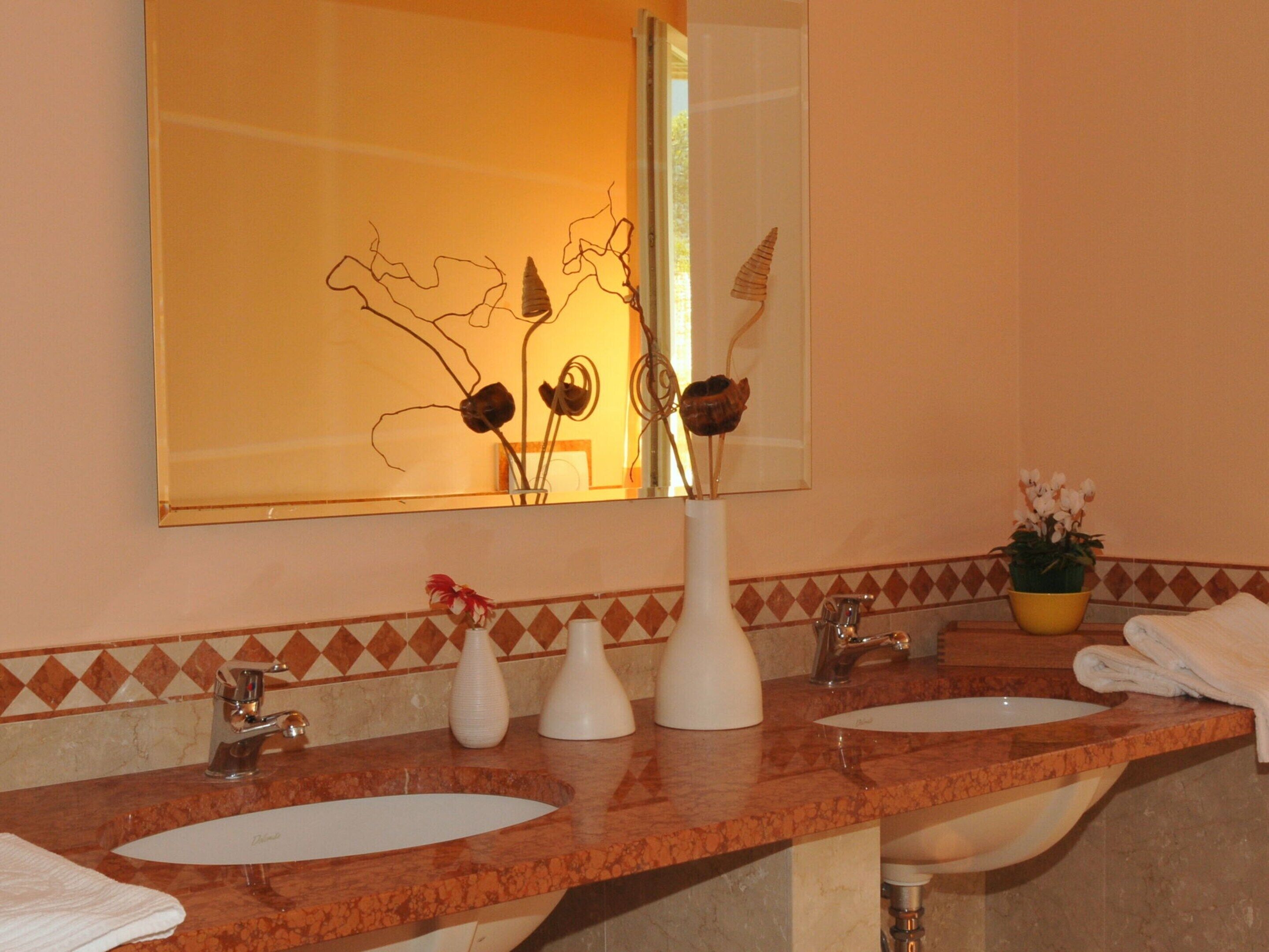 Un baño con dos lavamanos, un espejo y jarrones decorativos.