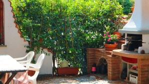 Un patio con un horno de ladrillo, una mesa con sillas y una planta en maceta.
