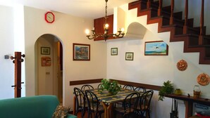 Un comedor con mesa y sillas, una araña y una escalera.