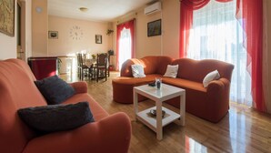 A living room with a sofa, a coffee table, and a dining area with chairs and a table. - Holiday Home Near Zadar With Private Pool (Posedarje)