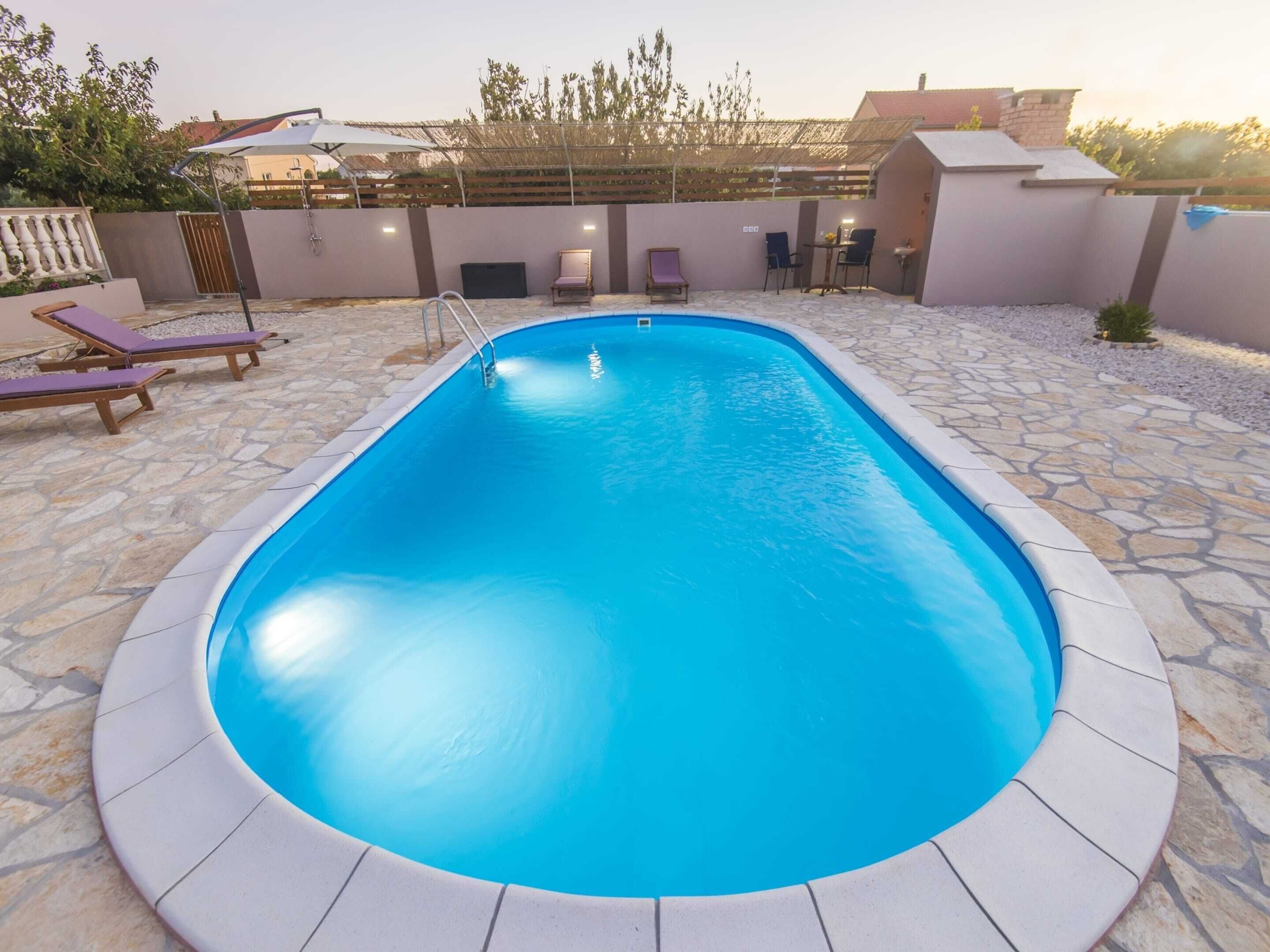 Una piscina rettangolare con un bordo in pietra.