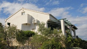 A white building with a green roof, a pergola, and a stone wall. - Holiday Home in Veli Rat Near Saharun (Sali)
