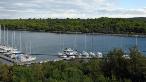 A marina with multiple sailboats docked, surrounded by dense green trees and hills in the background. - Holiday Home in Veli Rat Near Saharun (Sali)