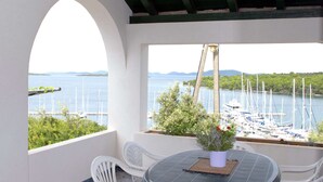 A balcony with a table and chairs, overlooking a marina with boats and a view of the water and distant mountains. - Holiday Home in Veli Rat Near Saharun (Sali)