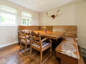 A dining area with a wooden table, chairs, a bench, and a horn mounted on the wall.