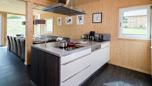 Une cuisine moderne dotée d’un îlot central, d’appareils électroménagers en acier inoxydable et de panneaux en bois.
