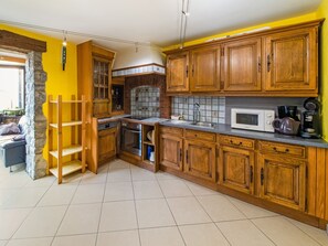 Eine Küche mit Holzausstattung, einer Mikrowelle, einer Kaffeemaschine und einer Steinwand.