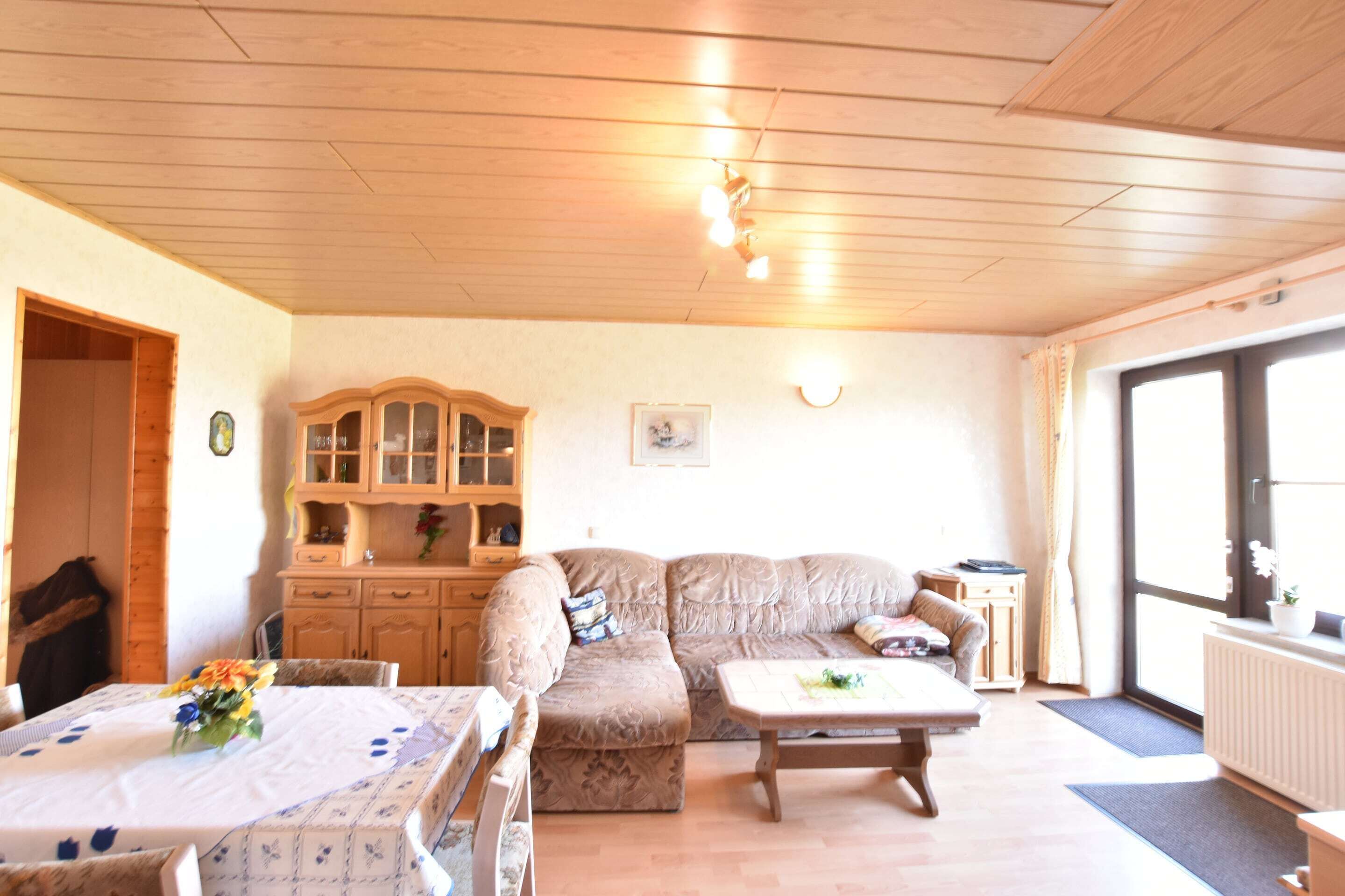 Un accogliente soggiorno con soffitto in legno, un divano, un tavolino da caffè e un tavolo da pranzo con sedie.