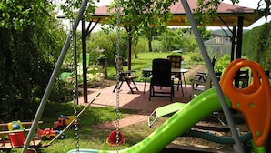 A children's play area with a swing set, slide, and picnic tables.