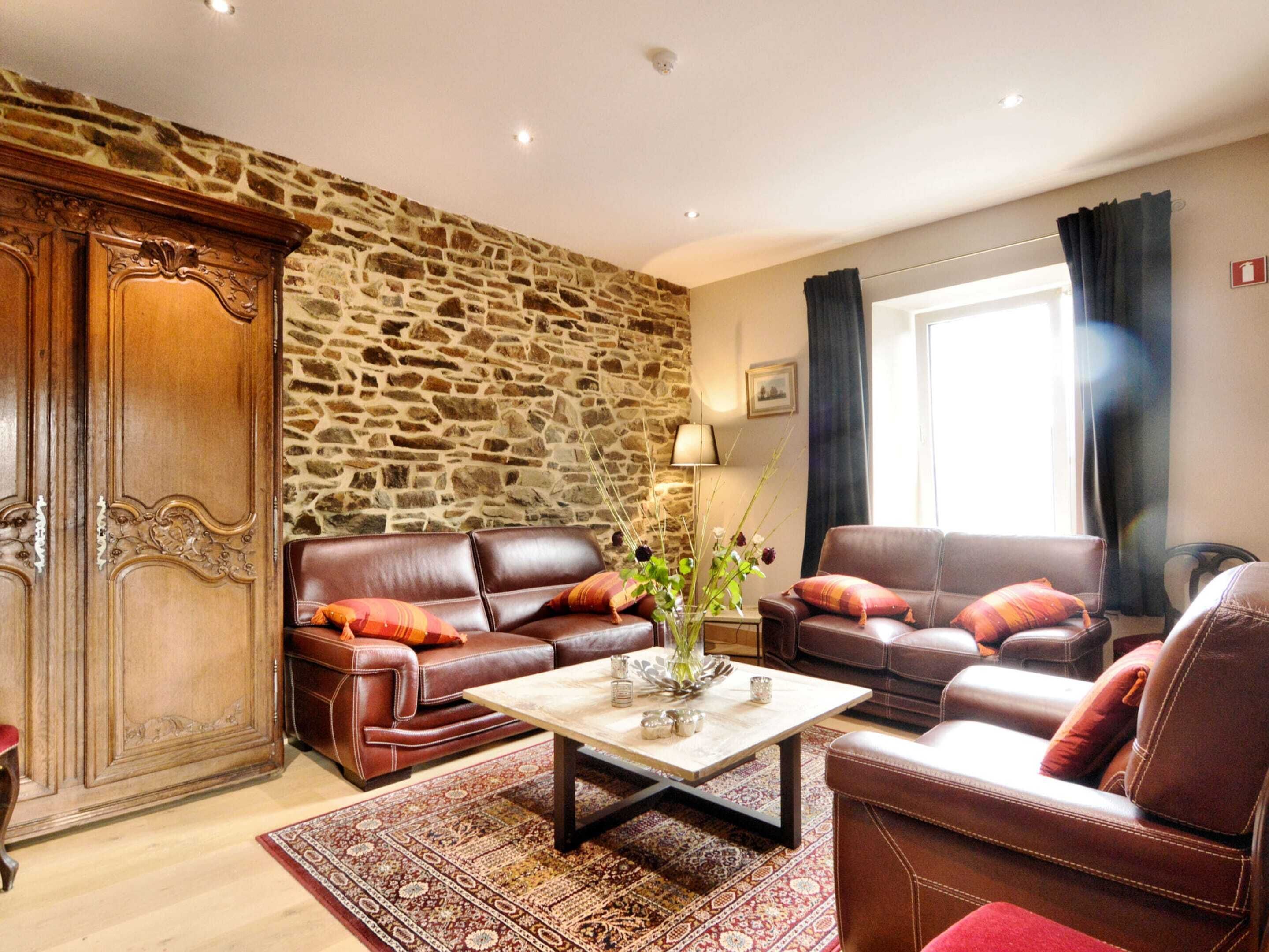 A living room with a stone wall, leather sofas, a coffee table, and a patterned rug.