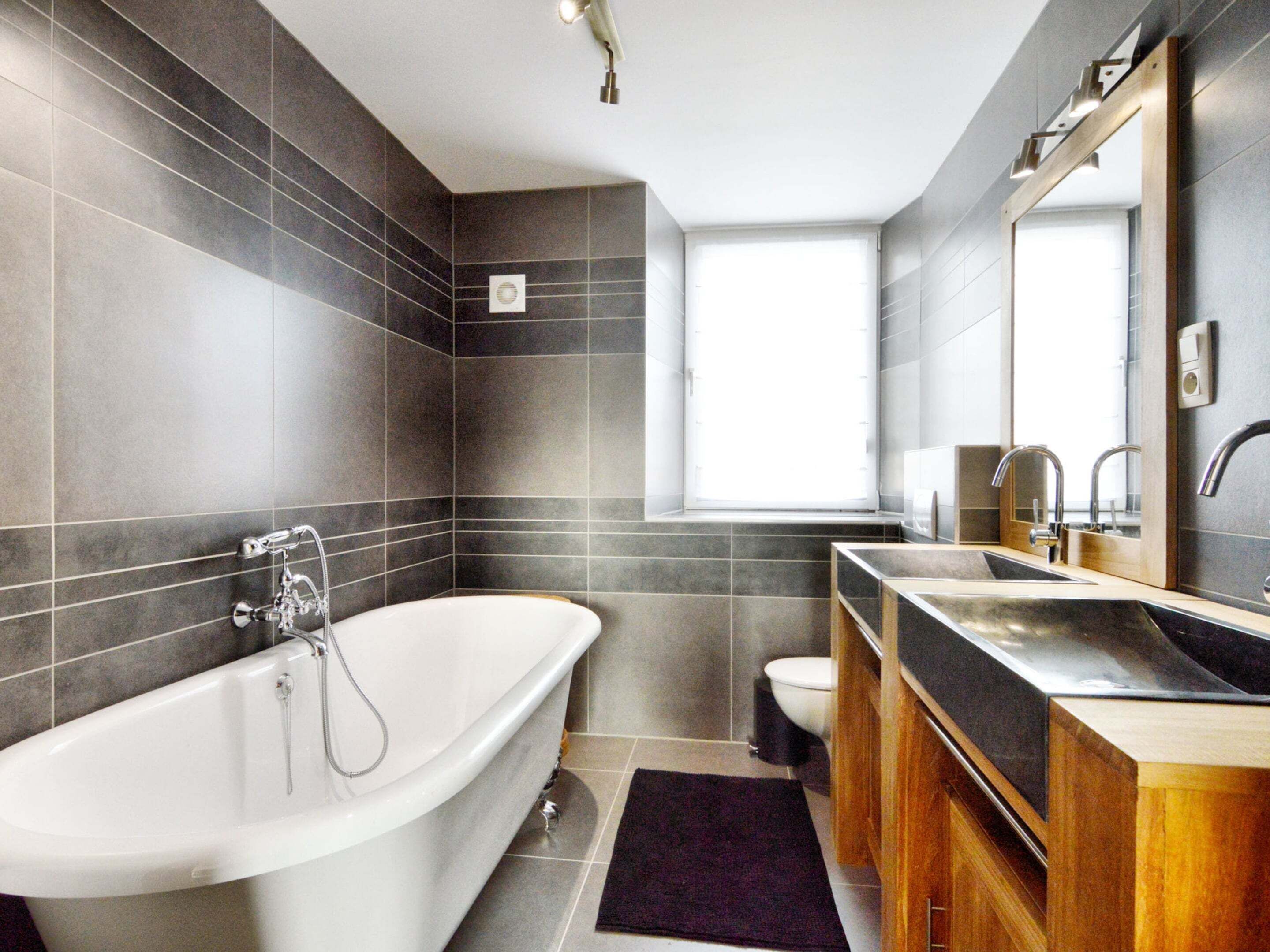 A modern bathroom with a freestanding bathtub, a vanity with a mirror, and a toilet.