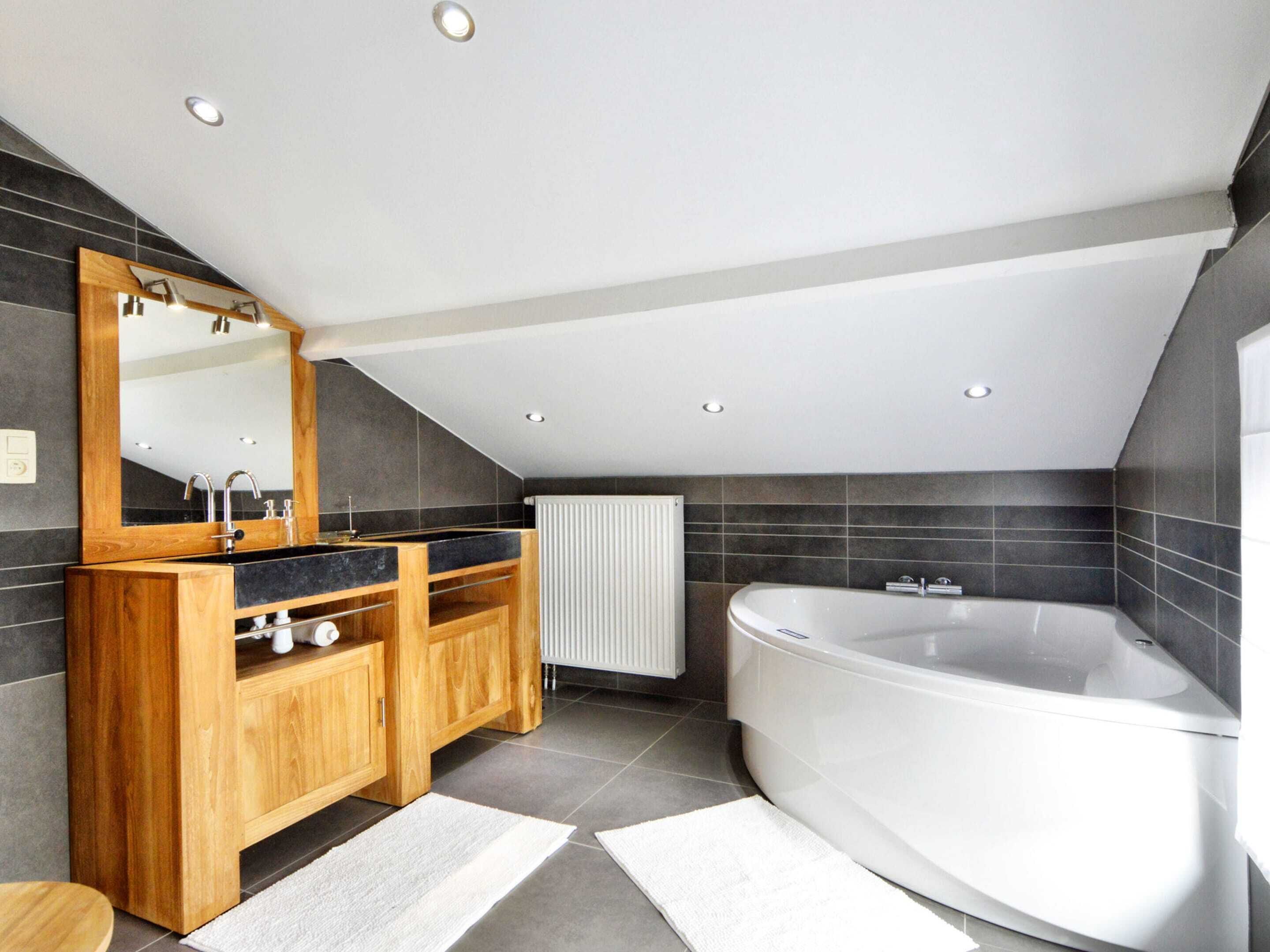 A modern bathroom with a freestanding bathtub, a wooden vanity with a mirror, and a radiator.