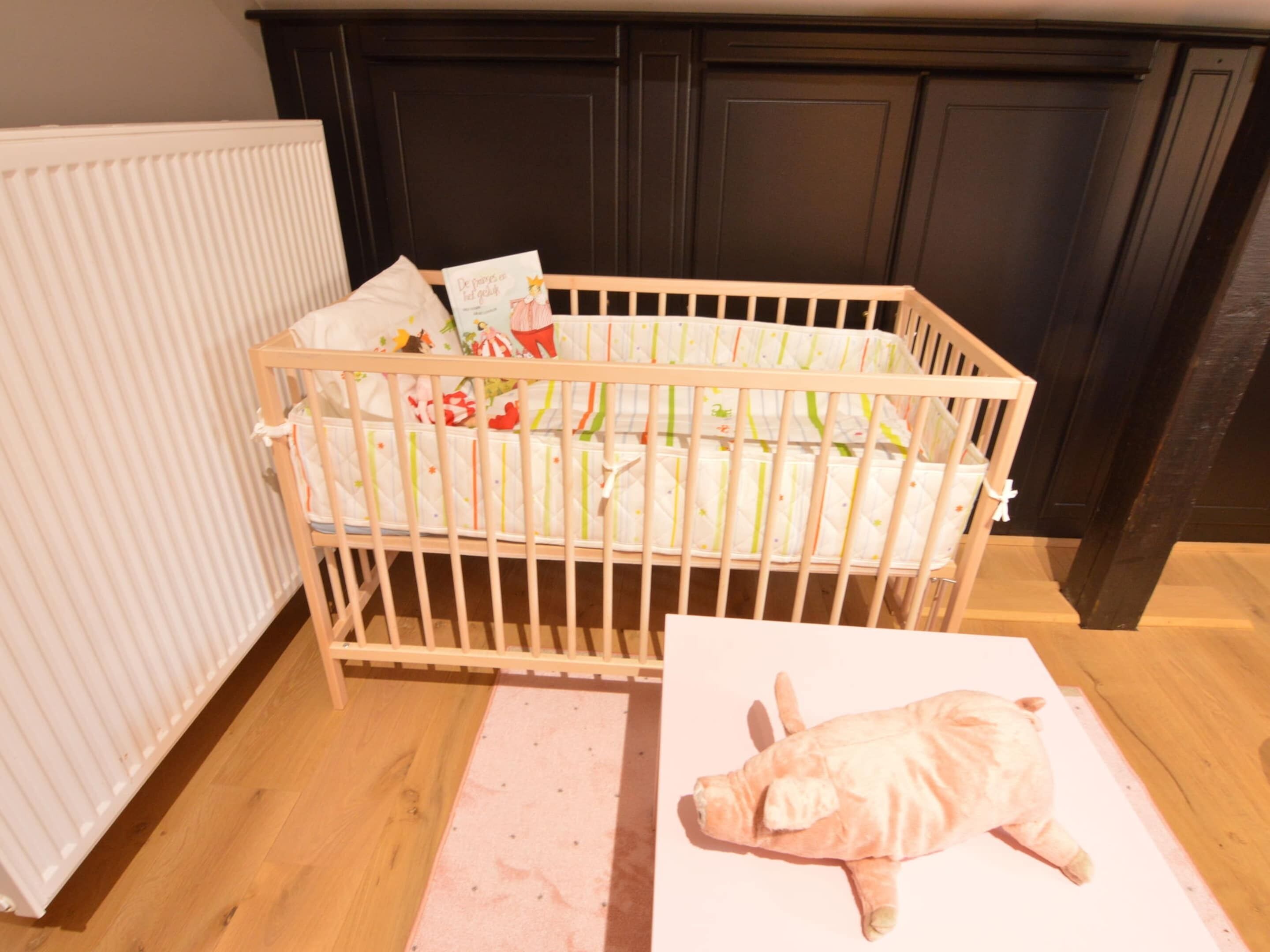 A crib with a baby animal plush toy beside it.