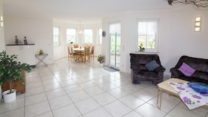 A spacious living area with a dining table, sofas, and a potted plant. - Ferienhaus in Hessen mit Grossem Garten (Voehl)