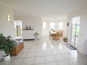 A spacious kitchen with white cabinets, a dining area with wooden chairs, and a potted plant.