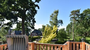 Een houten terras met een houten leuning, een comfortabele bank en een kleine tafel.