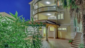 A multi-story building with balconies, a tiled entrance, and potted plants. - Lovely Apartment with Covered Terrace & Hot Tub (Crikvenica)