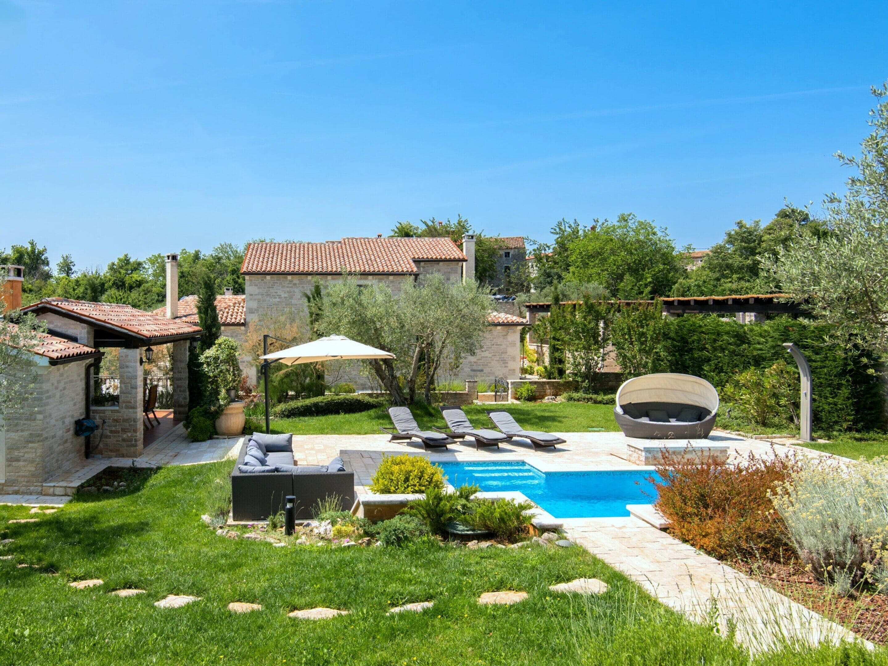 Un patio trasero con piscina, sillas de descanso y una pérgola.