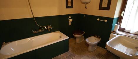 A bathroom with a bathtub, toilet, bidet, and sink.