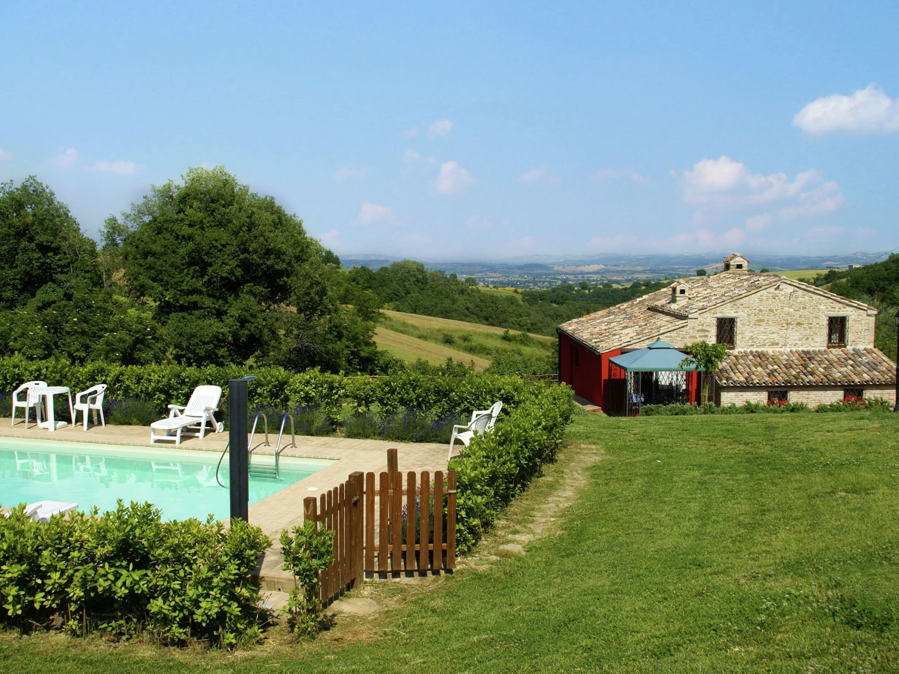 Ein Poolbereich mit Liegestühlen, ein Steinhaus und Blick auf die Landschaft.