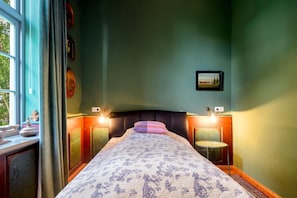 Un dormitorio con cama, mesitas de noche, una ventana y un cuadro colgado en la pared.