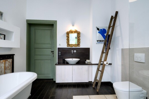 A bathroom with a green door, a white sink, a mirror, and a toilet. - Ferienwohnung in Steffenshagen mit Terrasse (Steffenshagen)
