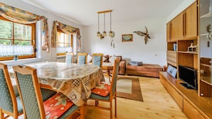 A cozy living room with a wooden dining table, chairs, a sofa, and a television. - Holiday Home in Jagersgrun With Sauna (Muldenhammer)